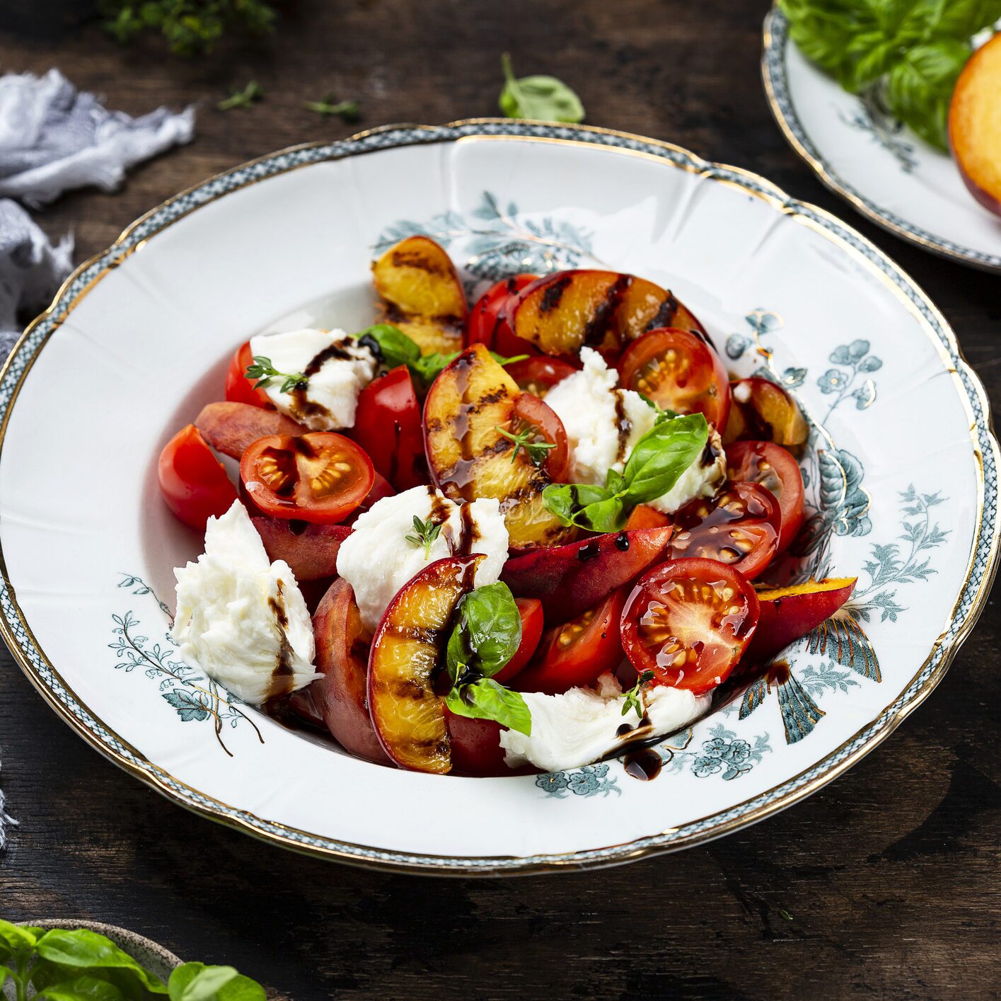 Grilled peach salad with mozzarella and tomatoes in a while bowl. 