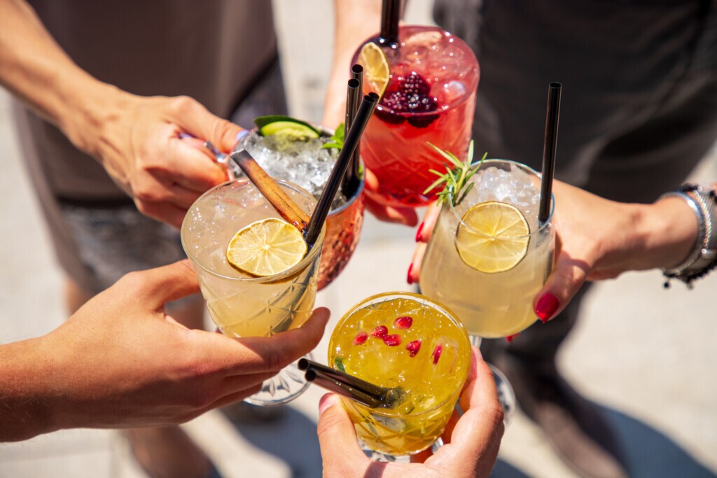 Five exotic cocktails on ice in hands joined in celebratory toast