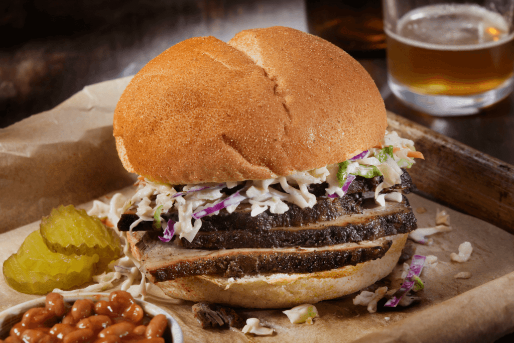 Dry Rubbed Beef Brisket Sandwich with Baked Beans, Creamy Coleslaw, Sweet Pickles and a Beer