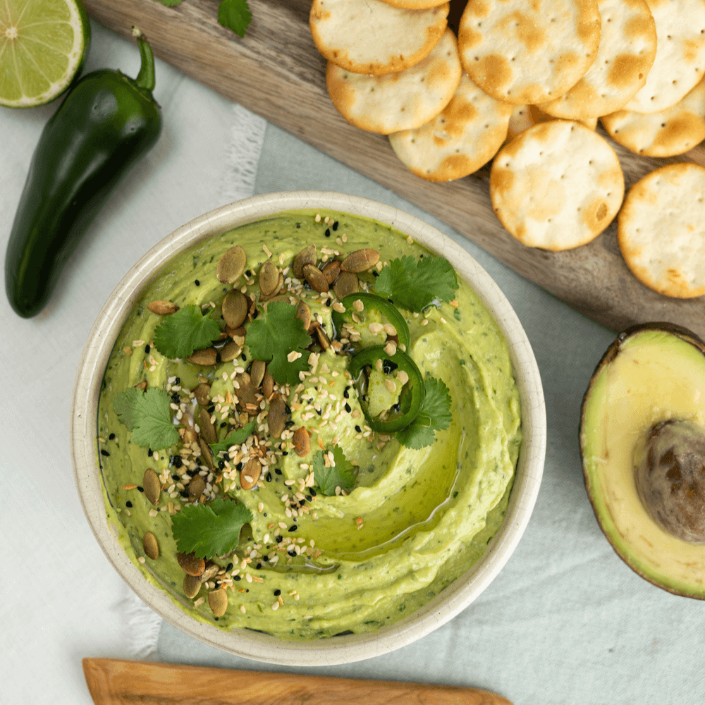 Overhead image of a bowl of avocado hummus garnished with pumpkin seeds and Farm Boy Everything Bagel Seasoning Blend.