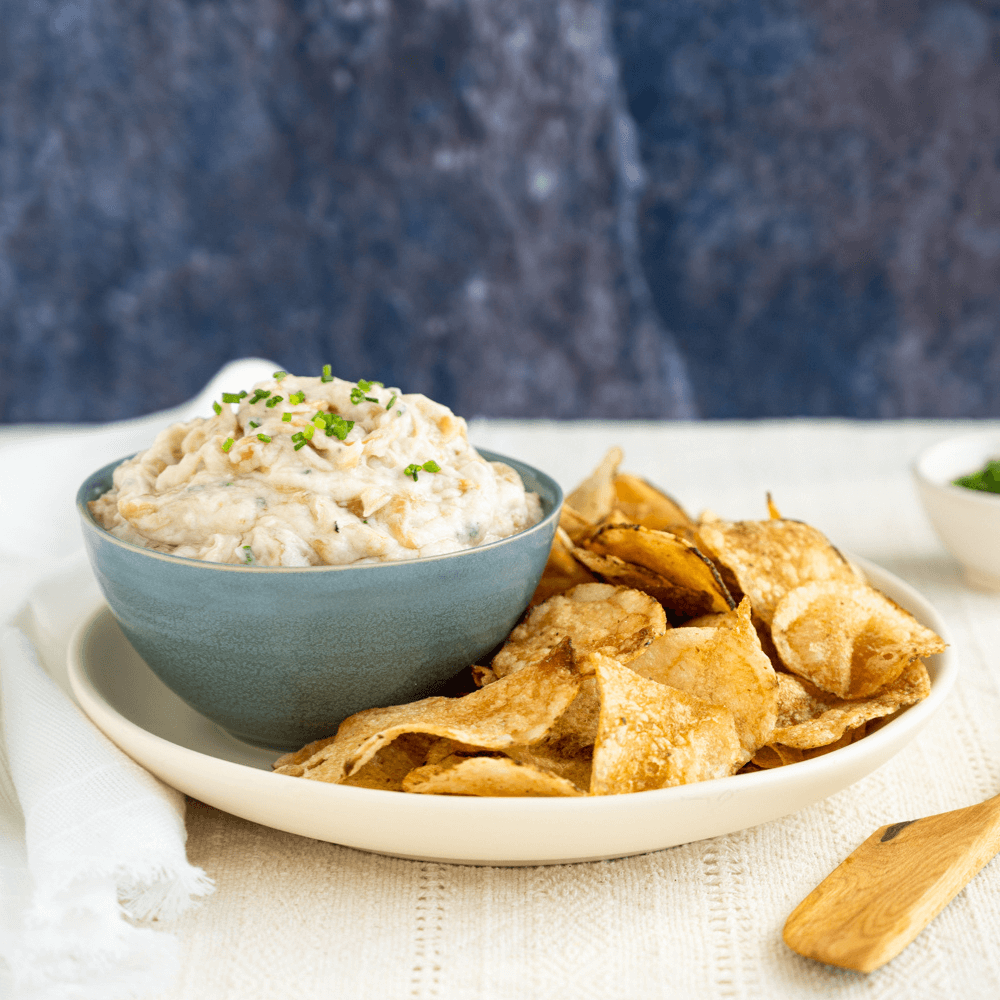 White plate with chips and a small blue bowl with caramelized onion chip dip.