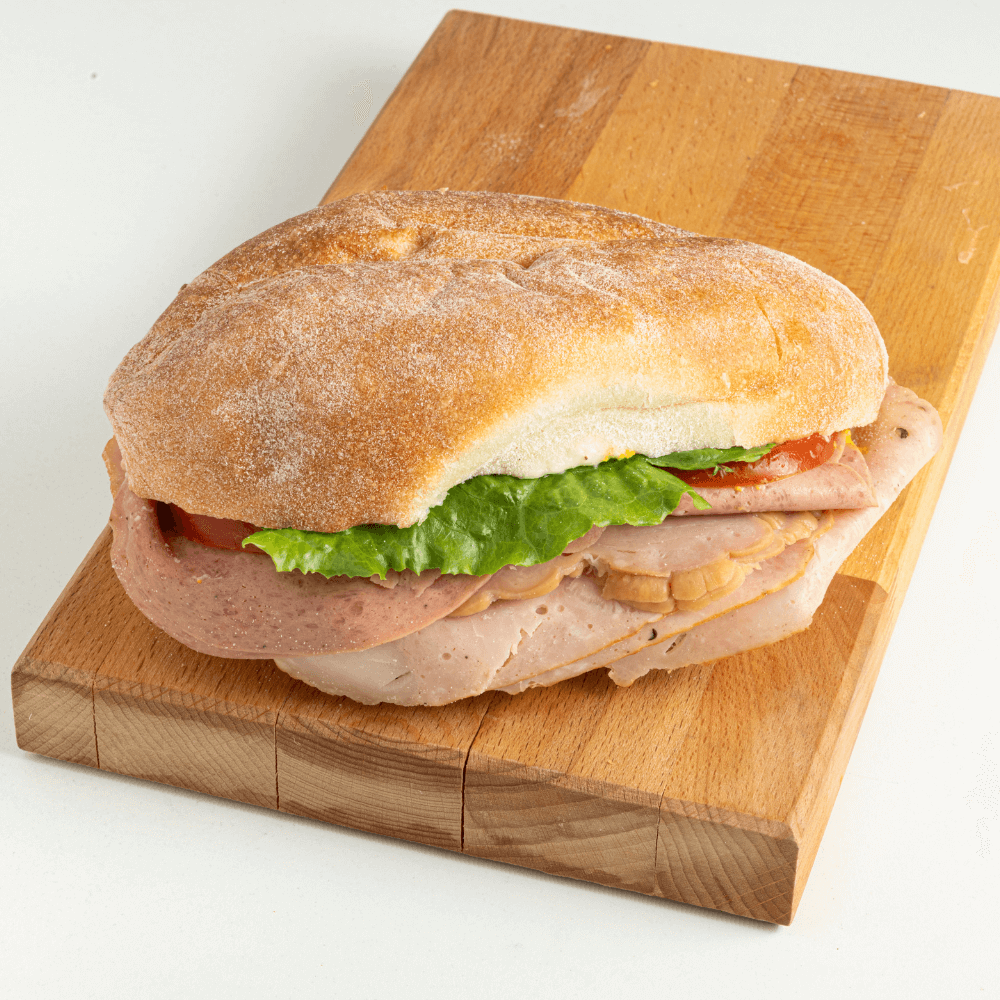 Dagwood substantial sub on wooden cutting board.