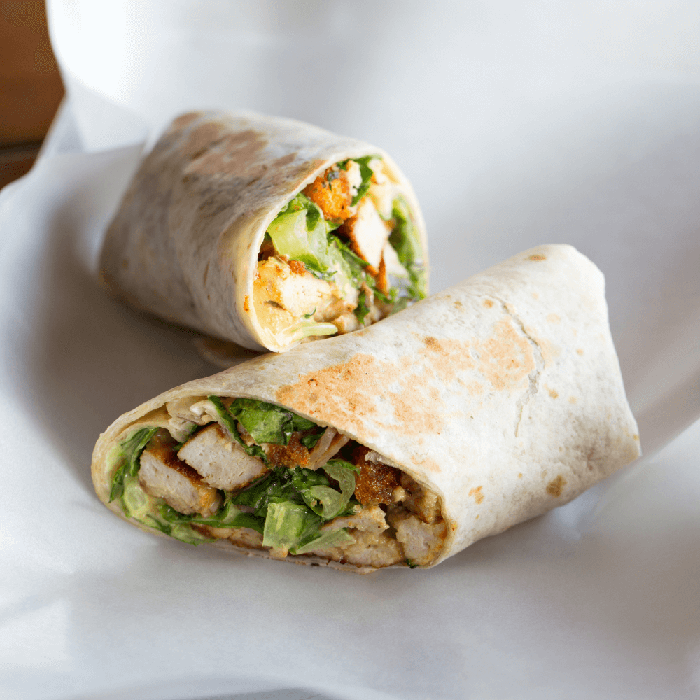 Chicken Caesar wrap cut in half on a white background.