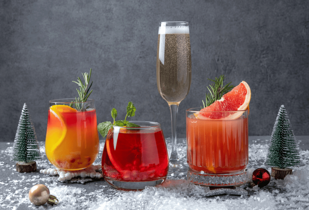 Festive cocktails with various citrus. Assortment of alcohol Christmas drinks. Pink and red sangria cocktails, champagne, pomegranate jingle and citrus tequila smash.