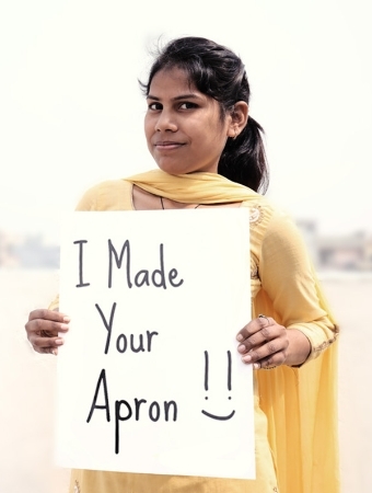 young woman holding sign that reads "I made your apron"