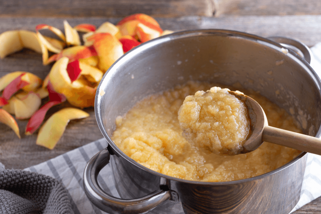 Pot filled with homemade applesauce scooped with a wooden spoon.