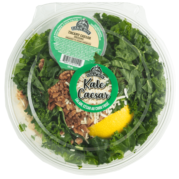 Fresh salad: Farm Boy™ Kale Caesar Salad. The salad is a bed of kale with bacon bits, parmesan cheese, and a wedge of lemon visible.