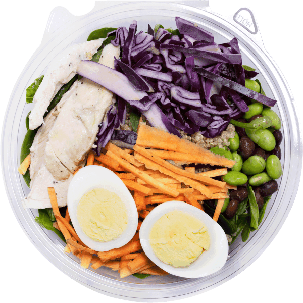 Farm Boy™ Power Protein Bowl. The bowl has cooked chicken, sliced hard boiled eggs, shredded carrots, shredded purple cabbage, and edamame.