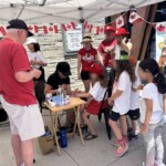 Families waiting in line to have their faces painted by a professional.