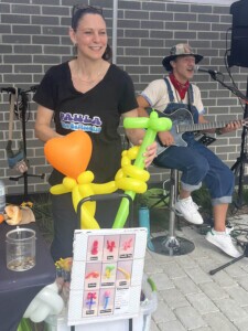 Two performers. One making balloon animals and the other singing with a guitar.