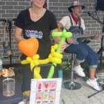 Two performers. One making balloon animals and the other singing with a guitar.