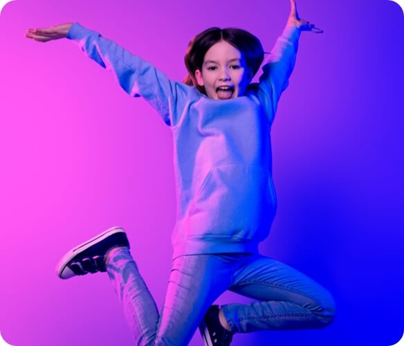 Image of a girl jumping up with her arms in the air.