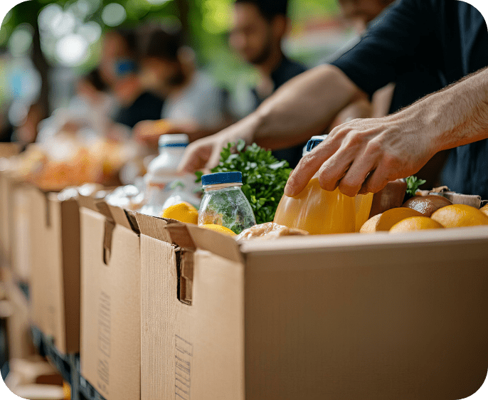 person placing food into a box along with others in the background