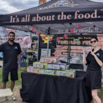 Two Farm Boy employees posing in front of the event table. One the table are free drinks.