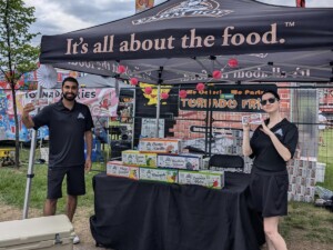 Two Farm Boy employees posing in front of the event table. One the table are free drinks.