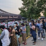 A long line of people stand waiting for a free Farm Boy drink.