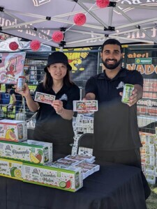 Two Farm Boy employees hold up the Farm Boy drinks while posing for a photo.