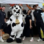 Farm Boy employees posing with Farm Boy's mascot Lulu in front of the event table.