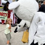 Farm Boy's mascot Lulu giving a child a high five.