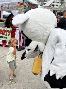 Farm Boy's mascot Lulu giving a child a high five.