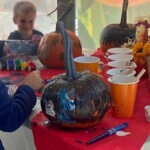 Children painting pumpkins at a table.