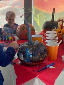 Children painting pumpkins at a table.