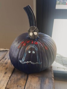 Completed design on a pumpkin. It's all black with an outline of a ghost and skull on top of the pumpkin. 