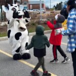 Farm Boy's cow mascot Lulu waving to children.