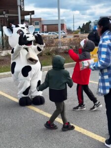 Farm Boy's cow mascot Lulu waving to children.